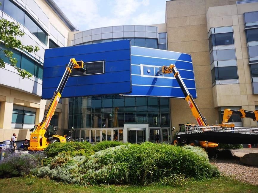 Blue AirPanel raised on a telehandler outside an office building