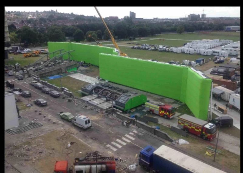 Aerial view of a long green AirWall running along a large exterior set at Pinewood Studios