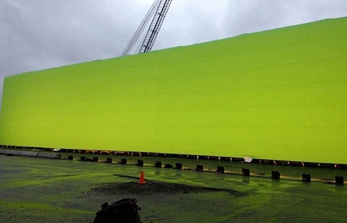 Green AirWall mounted on a trailer with a crane alongside